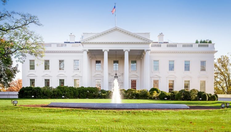 A large building with a grassy field with White House in the background